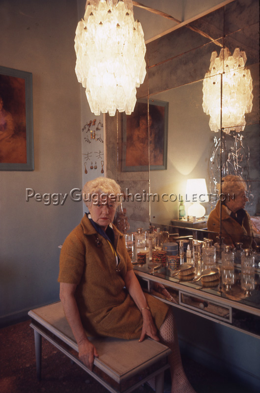 Peggy Guggenheim posa seduta al tavolo da toletta, nella sua camera da letto a Palazzo Venier dei Leoni.. Venezia, 1975. / diapositiva / Wilson, Ray; / 1975 