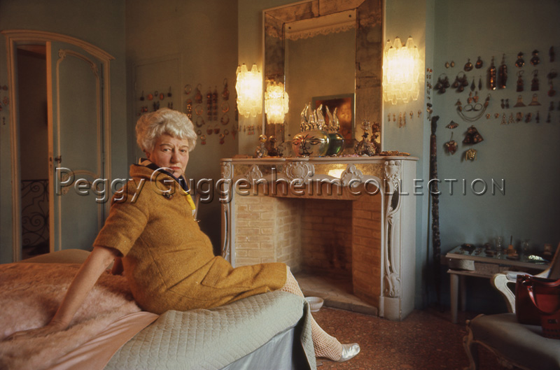 Peggy Guggenheim nella sua camera di Palazzo Venier dei Leoni. Sullo sfondo, ai lati del caminetto, è appuntata la sua collezione di orecchini. Venezia, 1975 / diapositiva / Wilson, Ray; / 1975 