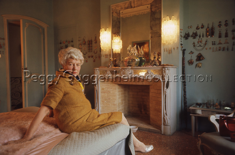 Peggy Guggenheim nella sua camera di Palazzo Venier dei Leoni. Sullo sfondo, ai lati del caminetto, è appuntata la sua collezione di orecchini. Venezia, 1975 / diapositiva / Wilson, Ray; / 1975 
